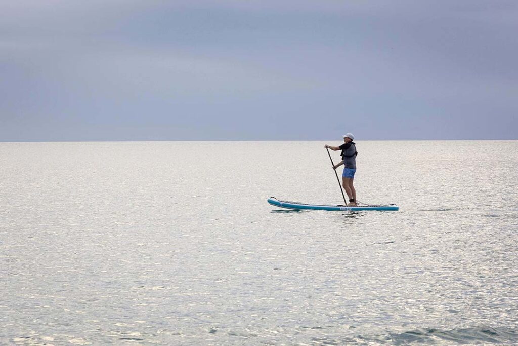Garanta sua aventura de luxo em alto-mar! Mulher praticando SUP em Galápagos, uma das aventuras de luxo em alto-mar das expedições da Inguz.