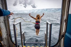 Viajante saltando de navio para o mergulho polar na Antártica.