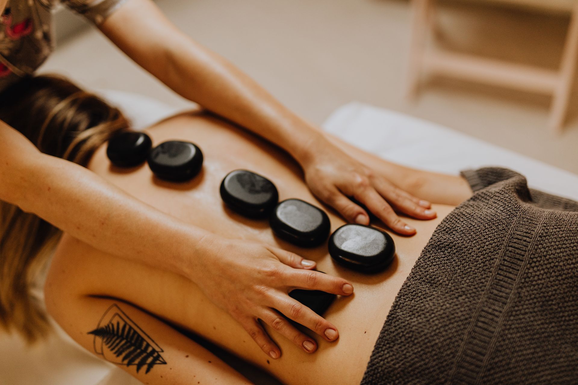 Pessoa recebendo uma massagem relaxante com pedras quentes, ilustrando o foco em bem-estar e relaxamento oferecido nas viagens da Inguz Expedições Marítimas.